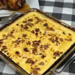 Cheesy Scalloped Potatoes in a baking dish, topped with bacon and served with a rotisserie chicken.